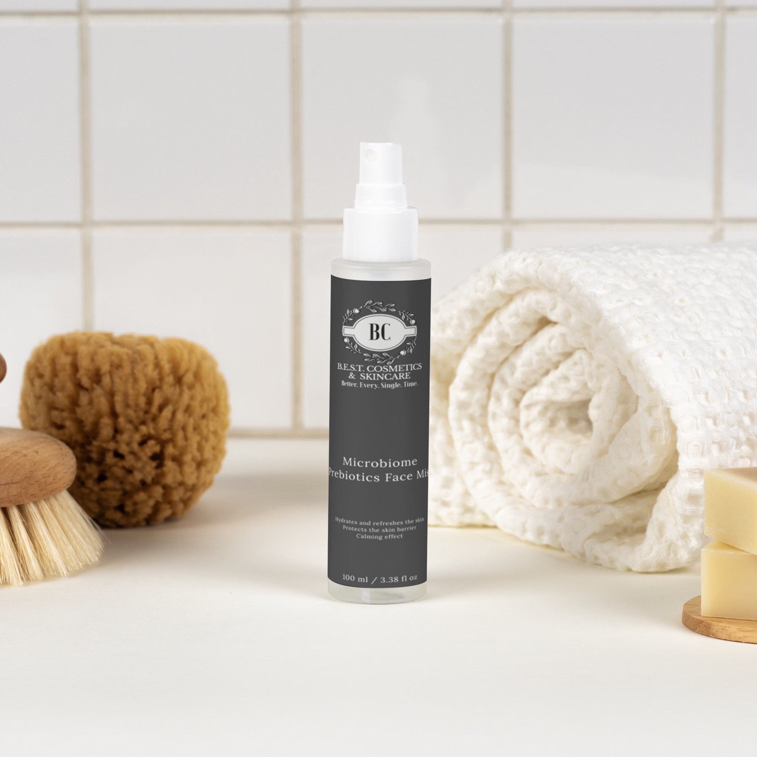 Bottle of body wash on a bathroom counter with a towel, soap, and scrubber in the background.